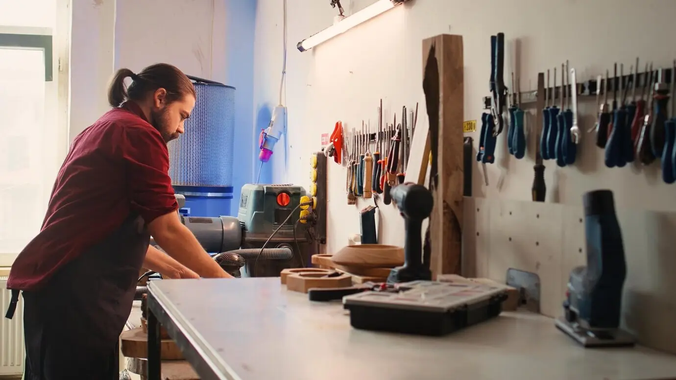 Handwerksfachkraft, die zusammen mit einer Kollegin oder einem Kollegen Qualitätssicherung an einem Schnittholzstapel durchführt.